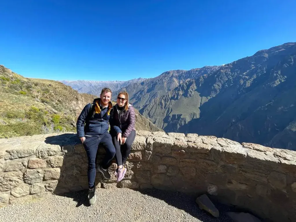 Pareja sonriente sentada en mirador del Cañón del Colca