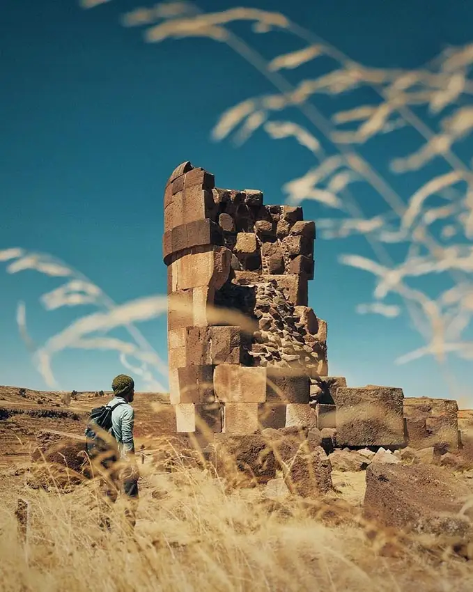 Persona observando una chullpa en ruinas en Sillustani, Puno.