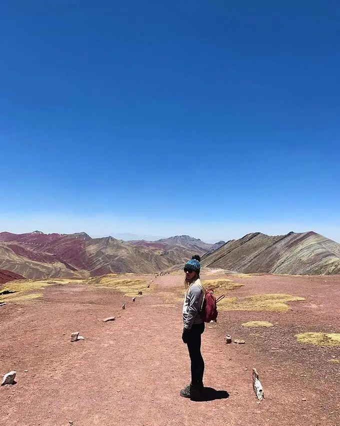 Turista apreciando a vista panorâmica das coloridas Montanhas Palcoyo.