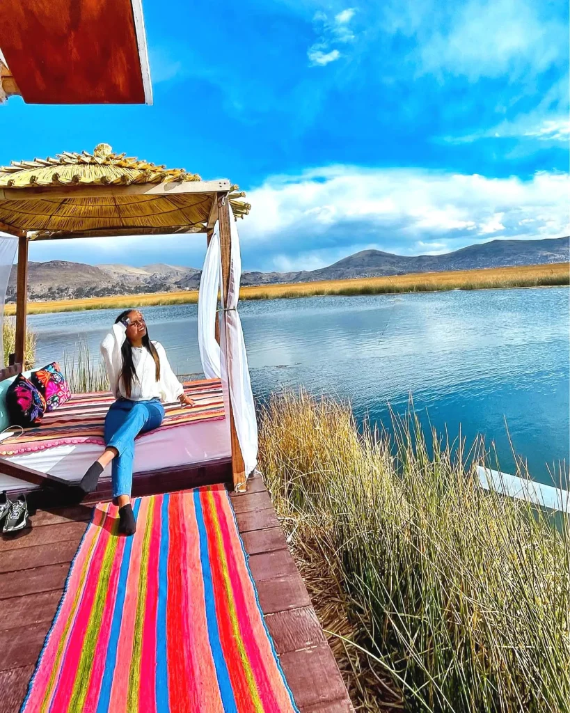 Mujer relajada junto al lago Titicaca sobre una terraza de madera.