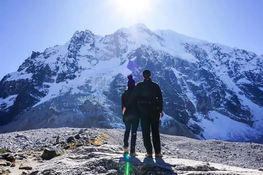 Pareja de espaldas contempla la imponente montaña nevada del Salkantay en Perú.
