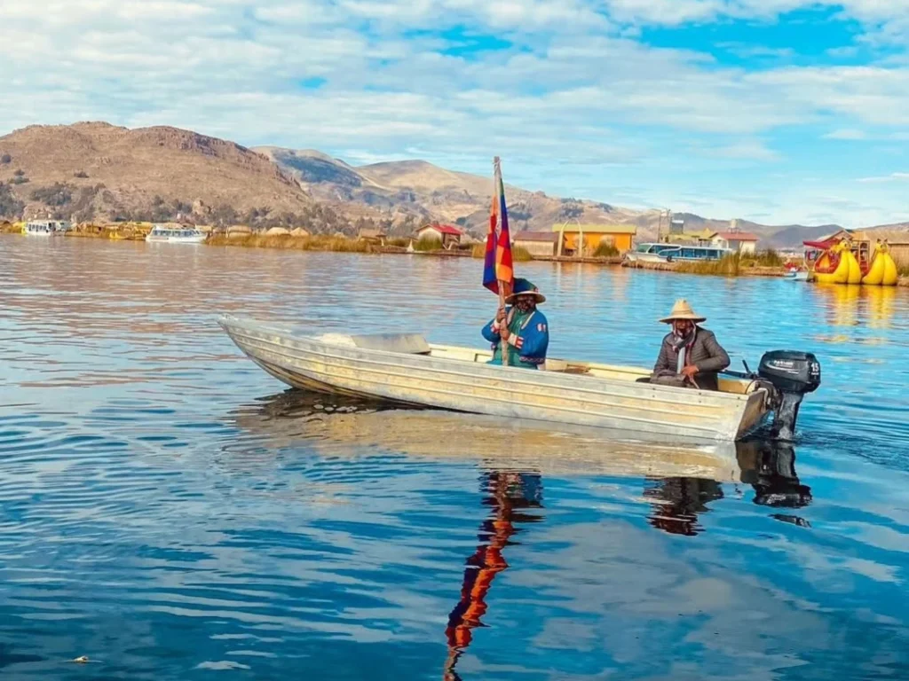 Dos hombres navegan en bote con bandera en el lago Titicaca, Puno