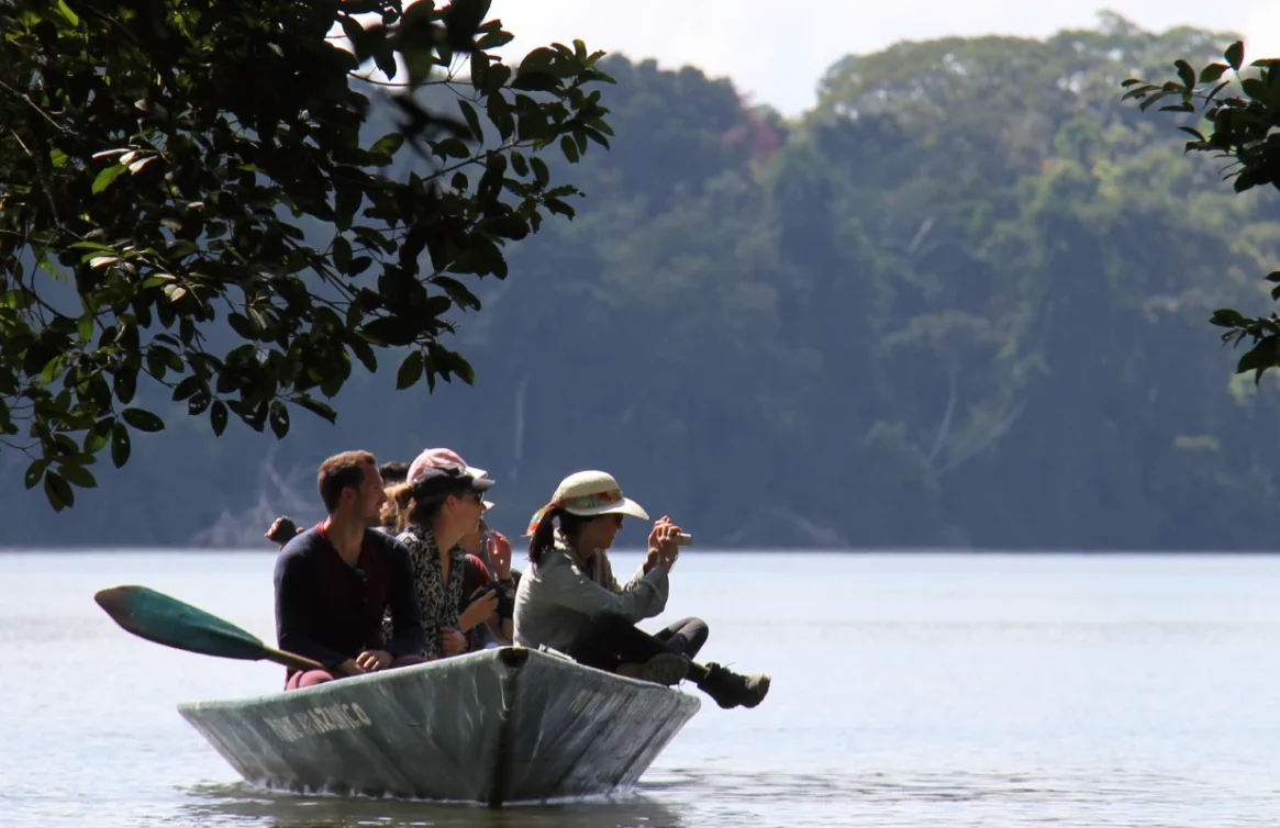 Pessoas passeando de barco em um rio na floresta amazônica.