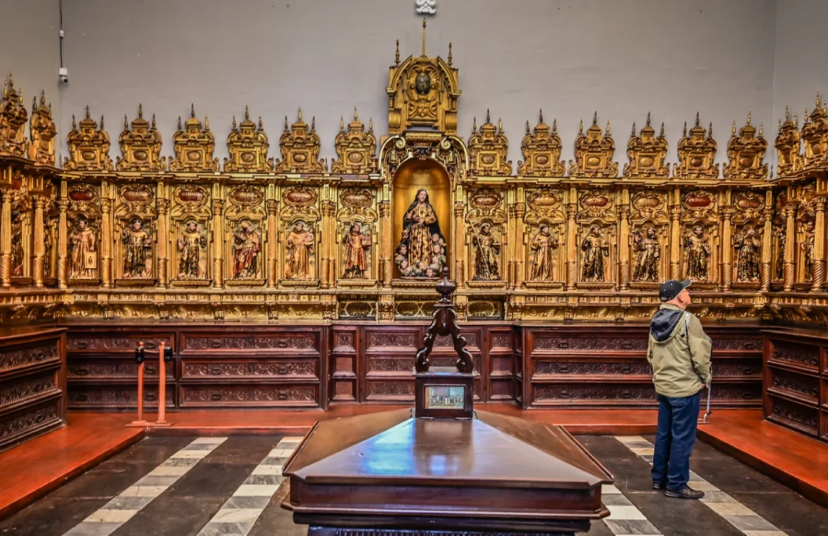 Persona observando un altar dorado tallado en el Convento de San Francisco, Lima.