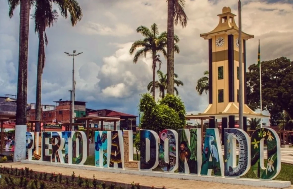 Letras coloridas de Puerto Maldonado e uma torre do relógio na praça