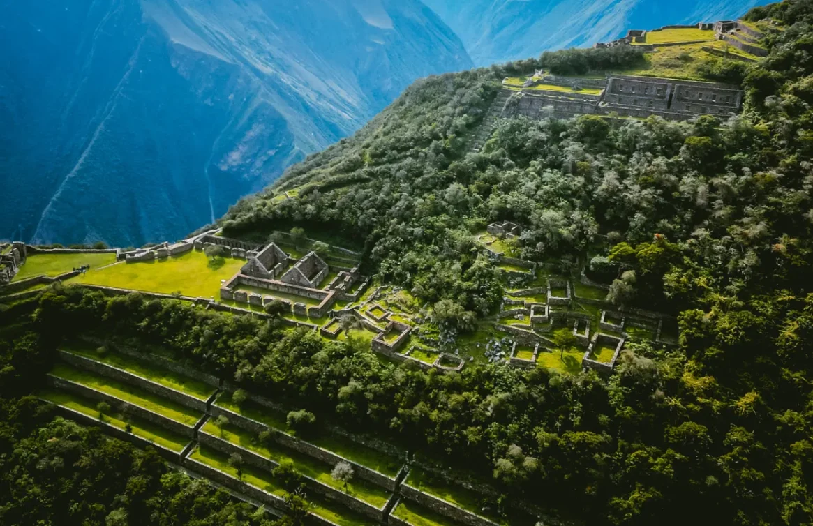 Vista aérea das ruínas de Choquequirao entre montanhas e vegetação.