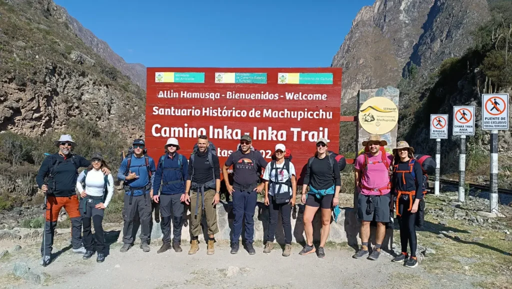 Grupo de excursionistas frente al letrero “Camino Inka – Inka Trail” del Santuario Histórico de Machu Picchu en Piscacucho (Km 82), Cusco, Perú.