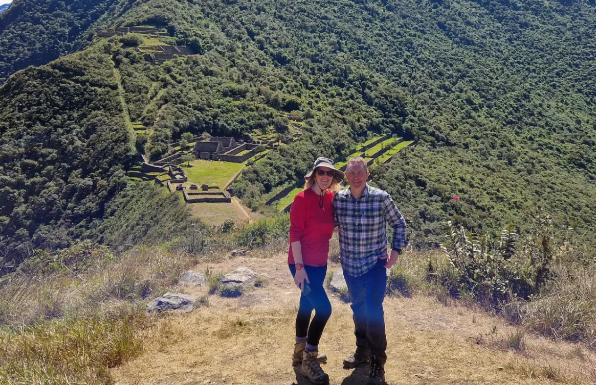 Um casal de caminhantes posando em frente às ruínas de Choquequirao, no meio das montanhas.