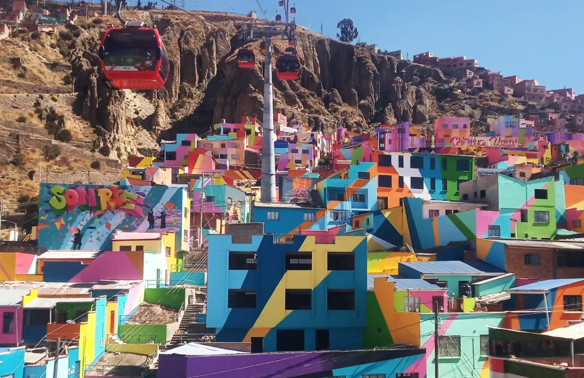 Casas coloridas em uma colina em La Paz com um teleférico vermelho passando por cima.