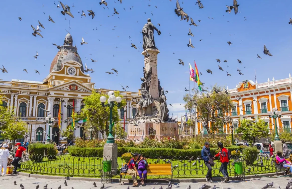 Praça central de La Paz, Bolívia, com palmeiras, jardins e edifícios coloniais.