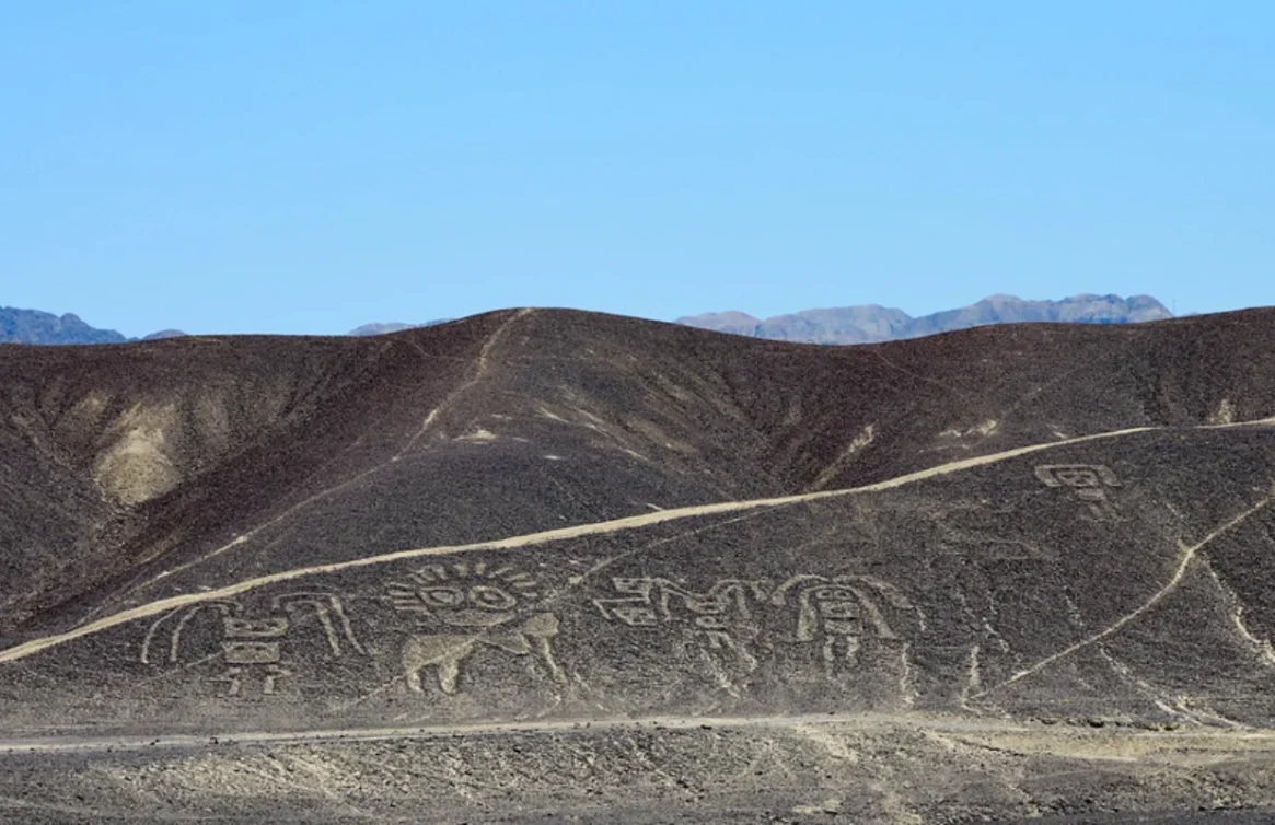 Líneas de Nazca con figuras de animales y formas geométricas en un desierto bajo cielo azul.