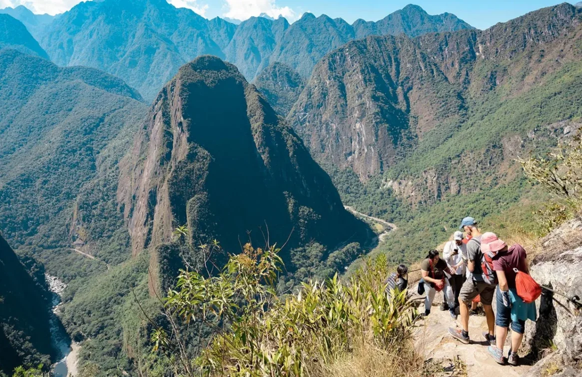 Grupo de caminhantes descendo em direção a Machu Picchu por uma trilha na montanha.