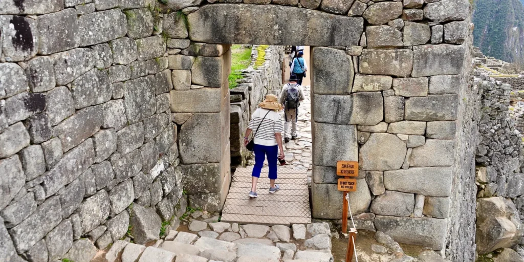 Turistas caminando a través de una puerta de piedra en Machu Picchu.
