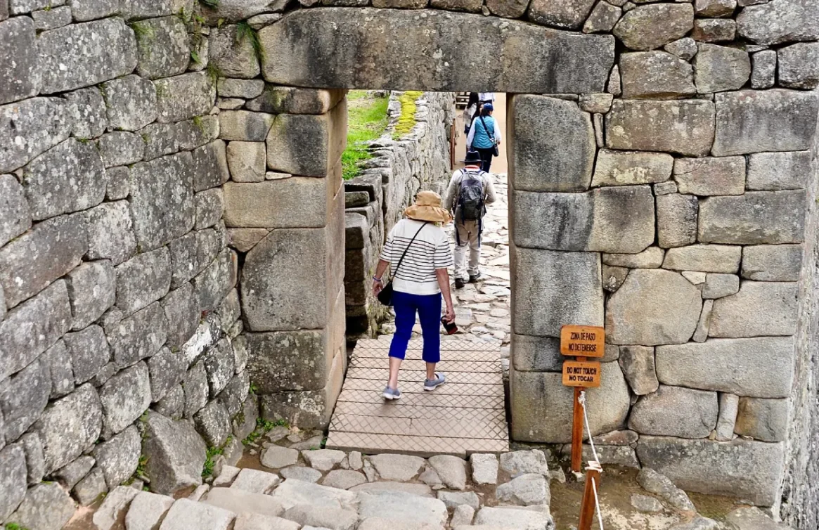 Turistas caminando a través de una puerta de piedra en Machu Picchu.