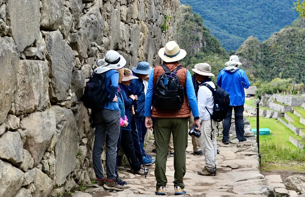 Grupo de turistas explorando las antiguas murallas y terrazas de Machu Picchu