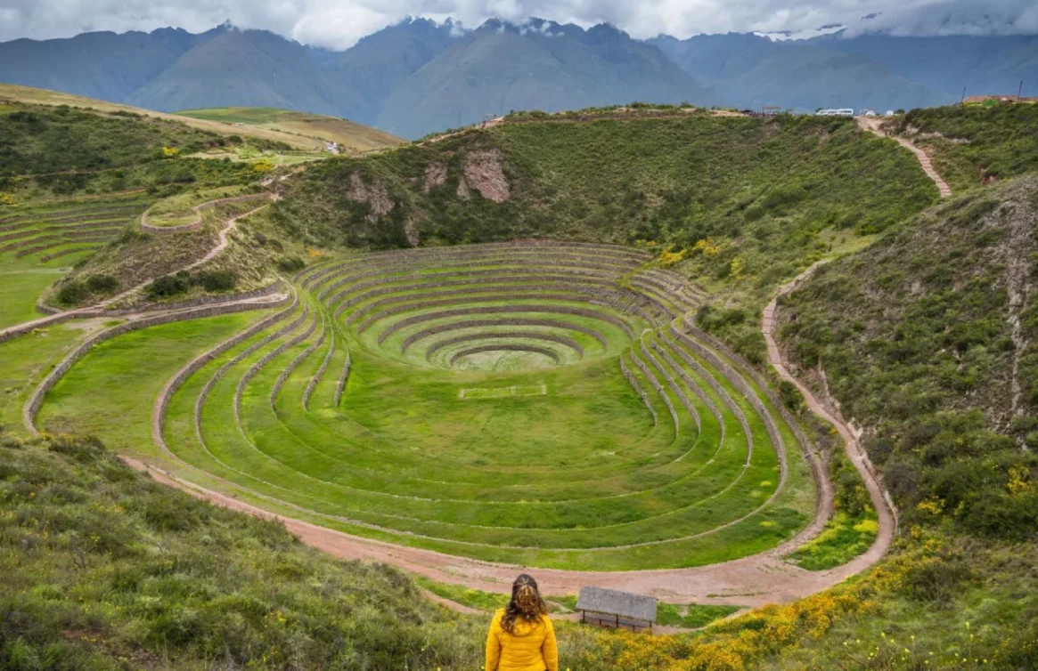 Turista apreciando os terraços circulares de Moray em um vale verde