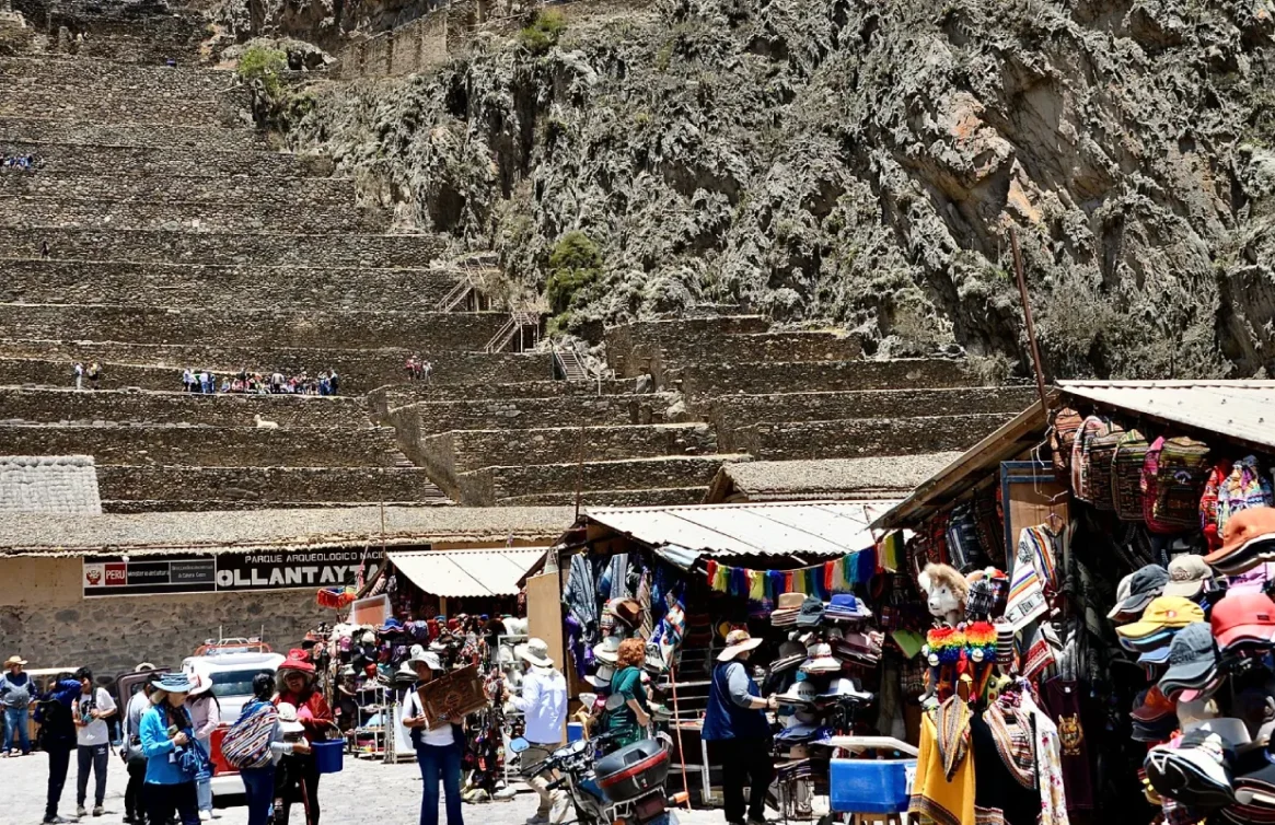 Mercado turístico em Ollantaytambo, com artesanato e lembranças em frente aos antigos terraços incas.