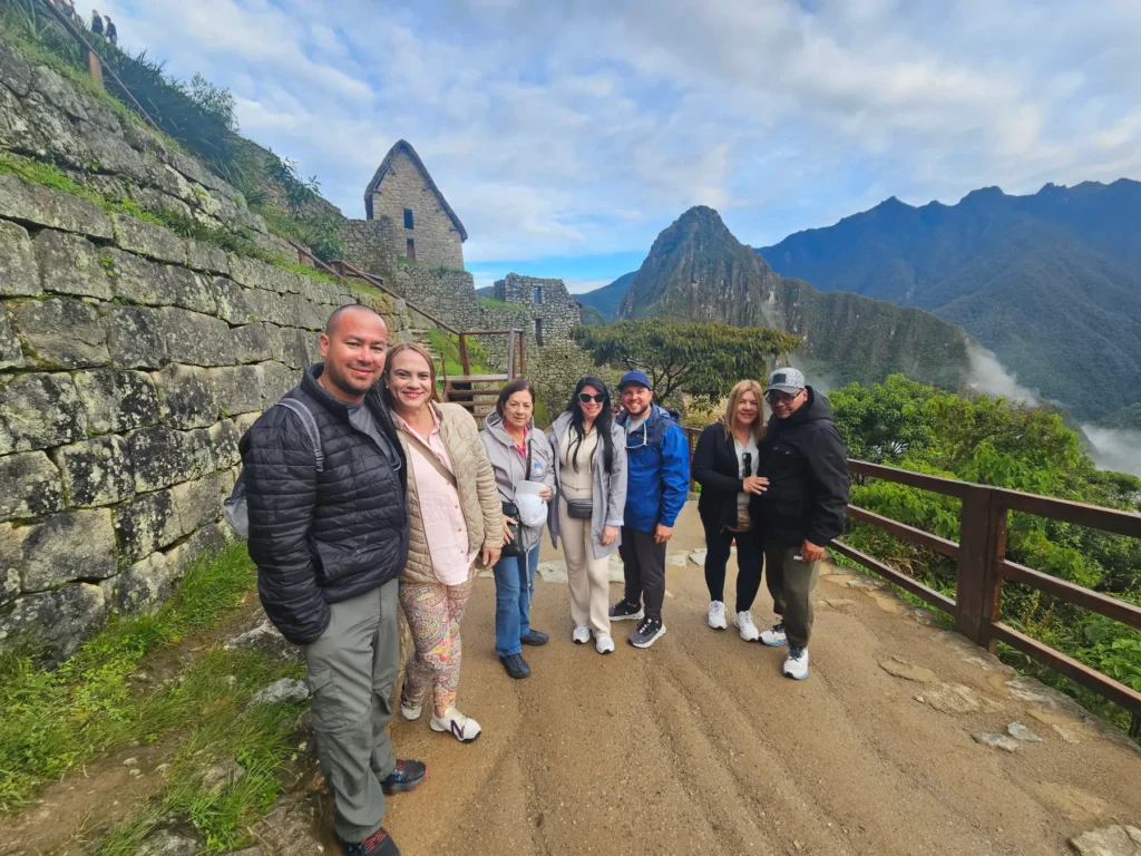 Grupo turistas diversos posa en ruinas Machu Picchu Cusco Perú muros incas montañas andinas paisaje natural.
