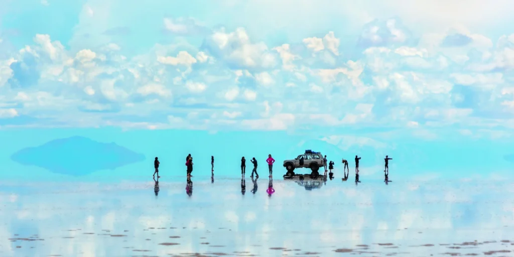 Personas y auto reflejados en el agua del Salar de Uyuni, Bolivia.