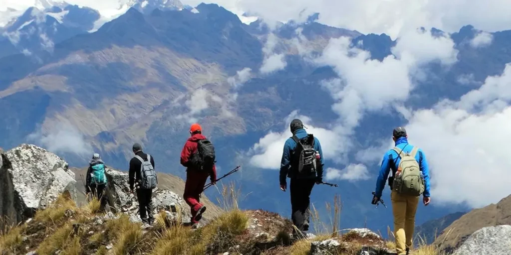 Excursionistas caminando por el sendero Salkantay rodeados de montañas nevadas.
