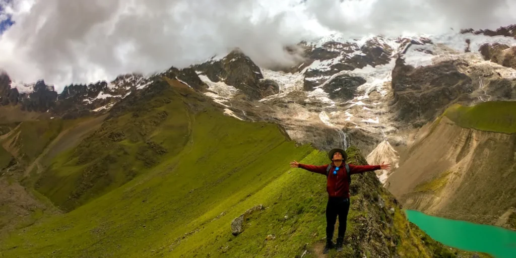 Turista frente a la Laguna Humantay y montañas nevadas.