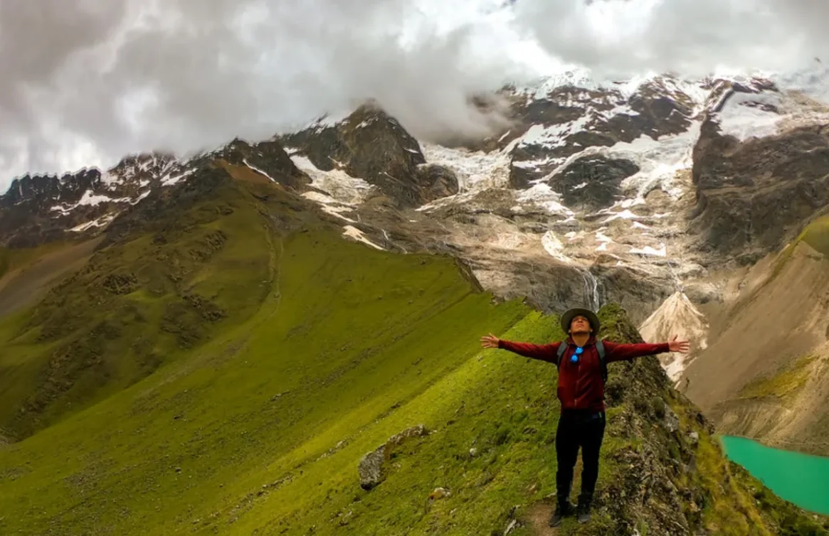 Turista frente a la Laguna Humantay y montañas nevadas.