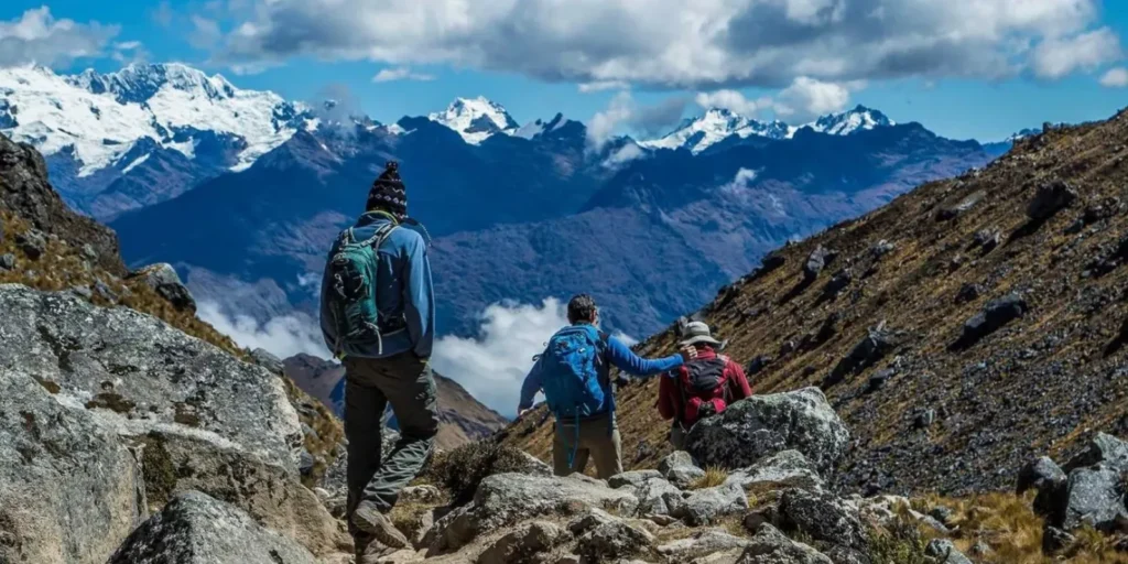 Turistas bajando por el sendero del Salkantay con montañas nevadas al fondo.