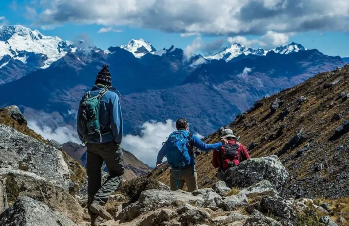 Turistas bajando por el sendero del Salkantay con montañas nevadas al fondo.