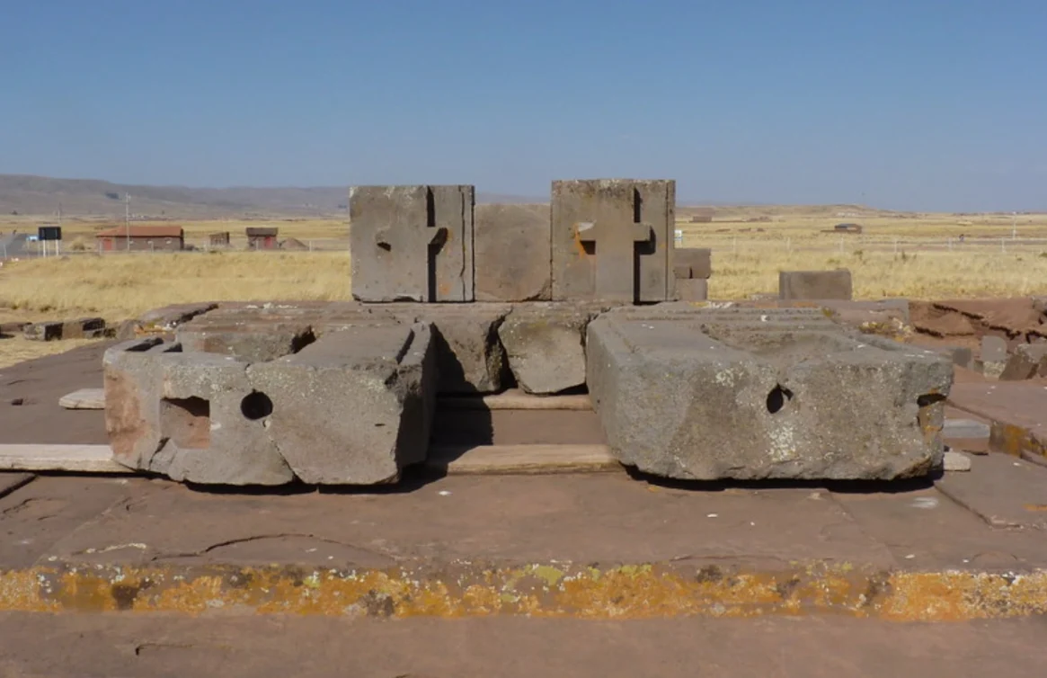 Blocos de pedra esculpidos de Tiwanaku em uma plataforma em um sítio arqueológico boliviano.