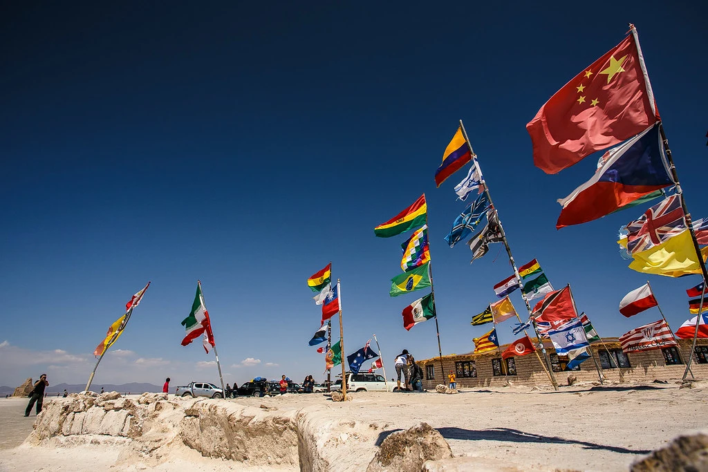 Bandeiras de muitos países tremulam sobre o Salar de Uyuni sob um céu claro.